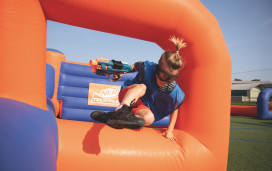 A guest jumping over the inflatables playing Nerf Training Camp