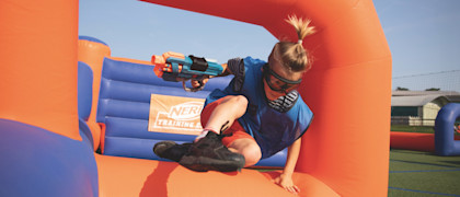 A guest jumping over the inflatables playing Nerf Training Camp