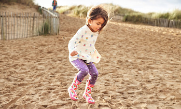 A girl jumps on the sandy beach in her wellies near Haven Golden Sands, Mablethorpe.