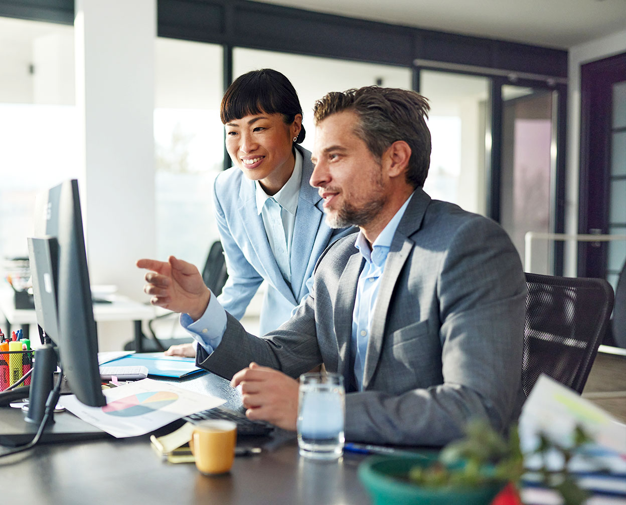 Two people speaking while looking at a computer screen