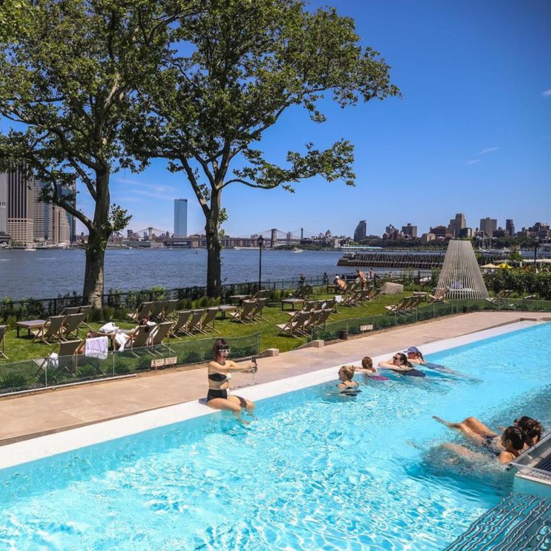 Visitors enjoying the outdoor pool with a view at QC Spa on Governors Island