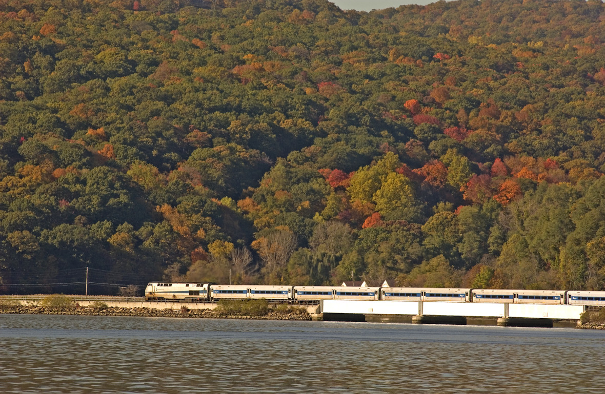 Metro-North locomotive and train traveling north along the Hudson with fall foliage in background
