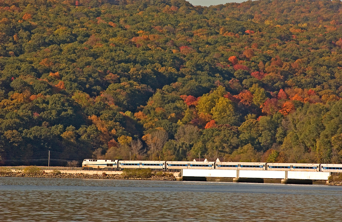 Metro-North locomotive and train traveling north along the Hudson with fall foliage in background