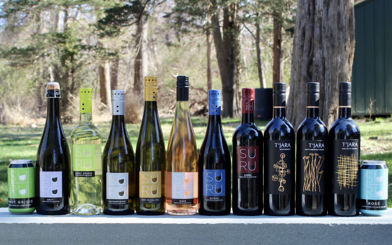 Ten different bottles of wines from Suhru Wines lined up on a table outdoors