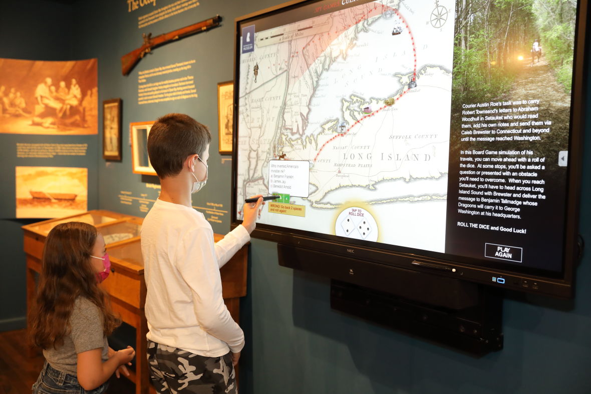 Two young visitors interact with an exhibit at the Three Village Historical Society