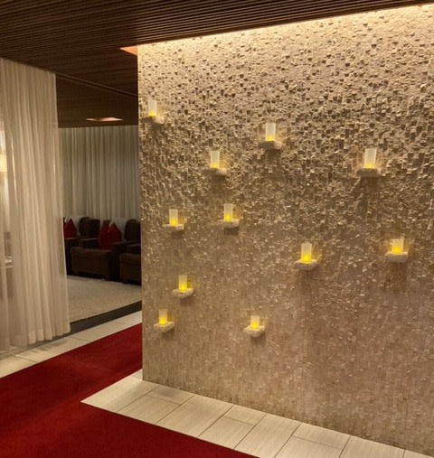 Decorative wall adorned with votive candles and a red carpet leading visitors into the Red Hots Spa