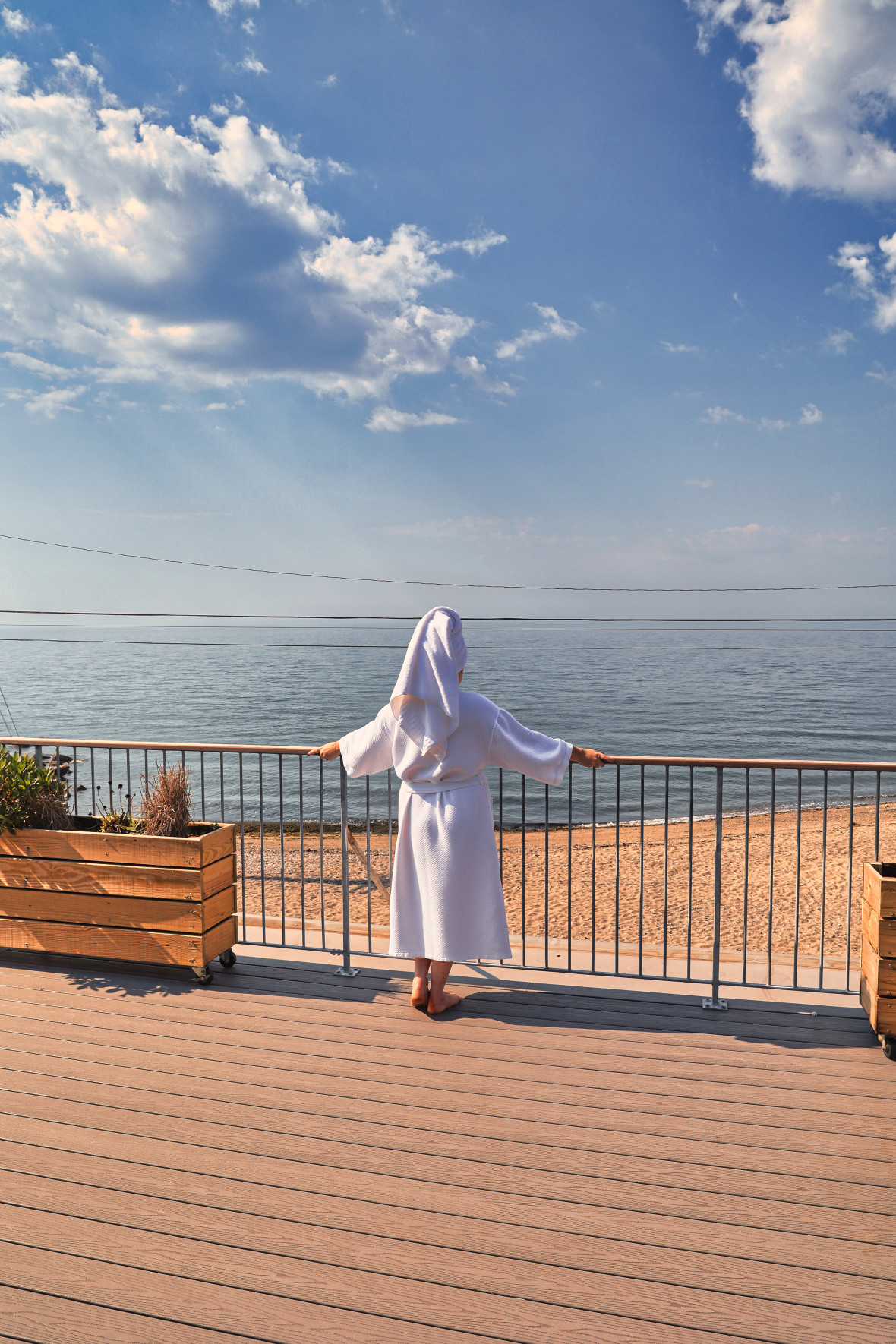 Woman in robe looking out at ocean from an expansive deck