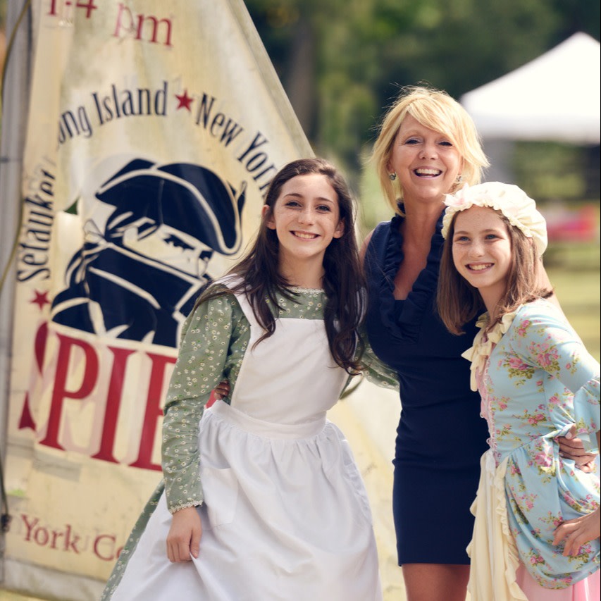 Happy customers pose in front of the Three Villages Historical Society, dressed in colonial garb