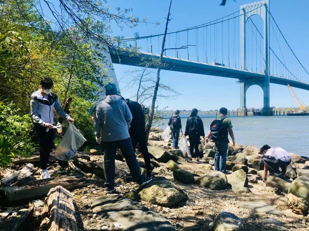 Group of volunteers clear the shore of the East River underneath the Bronx-Whitestone Bridge in Queens