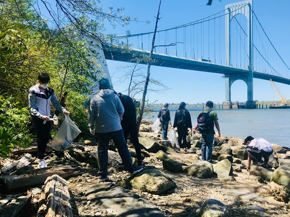 Group of volunteers clear the shore of the East River underneath the Bronx-Whitestone Bridge in Queens