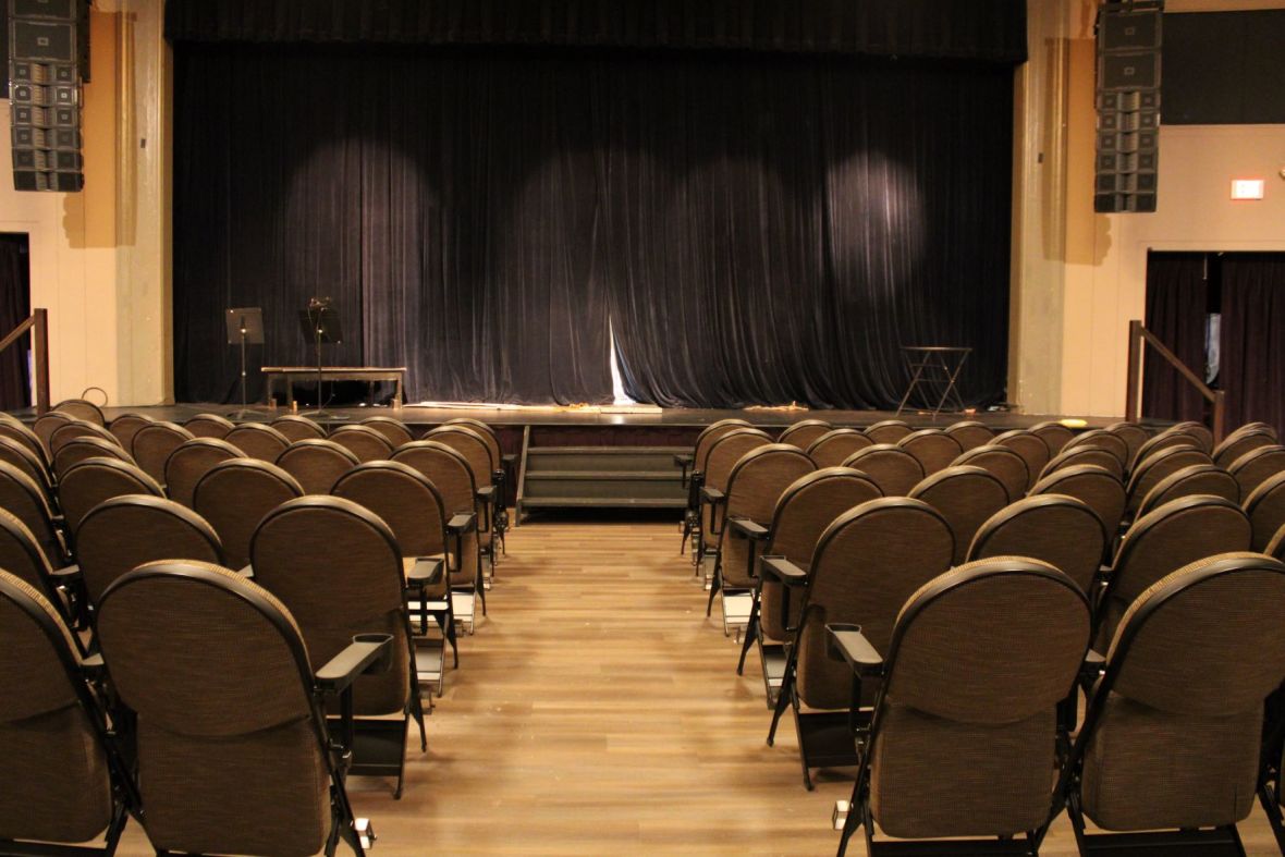 View of aisle with empty seats and a stage with a black closed curtain at Landmark on Main