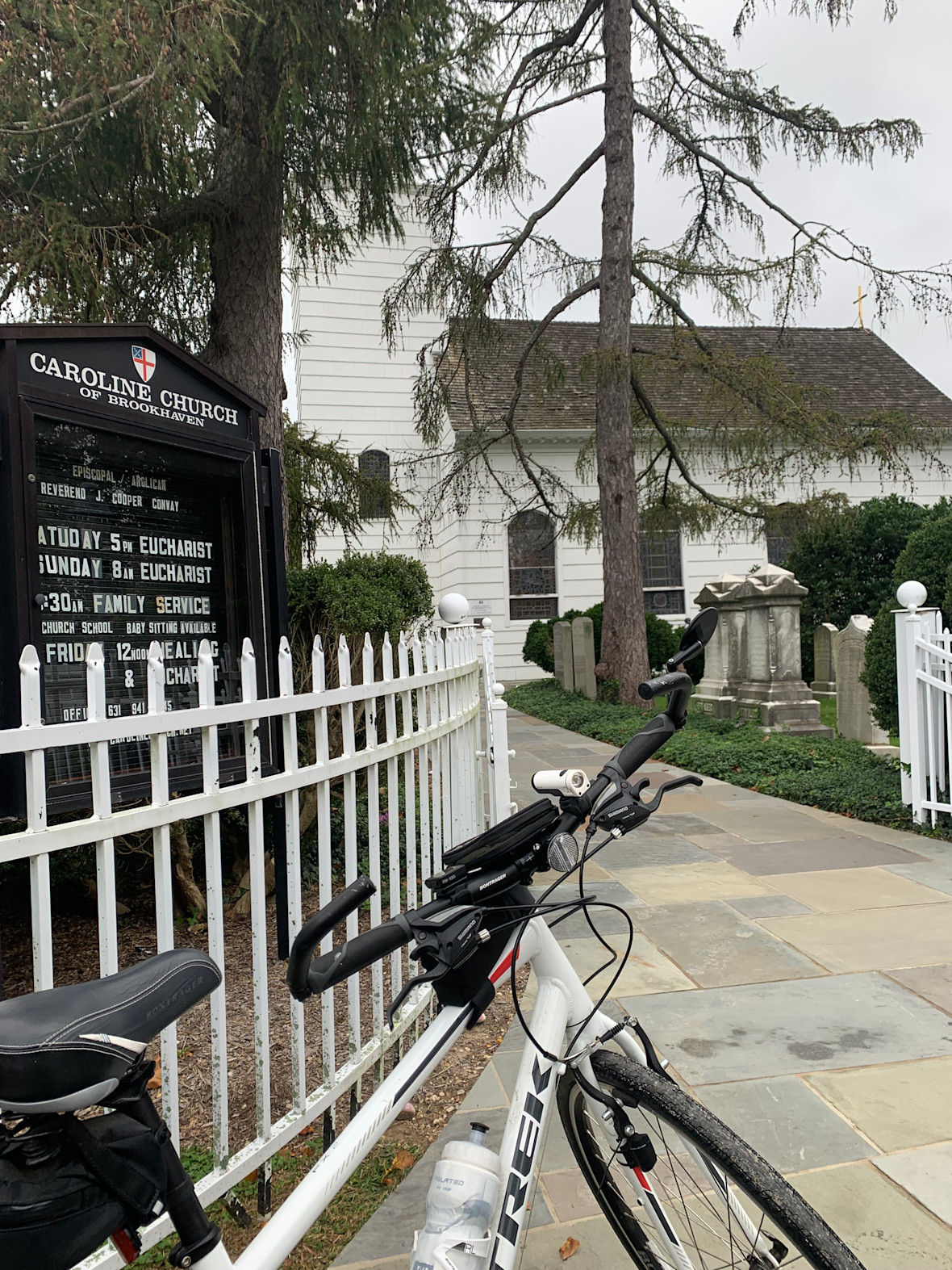 A bike leaning against the white picket fence of the Caroline Church of Brookhaven