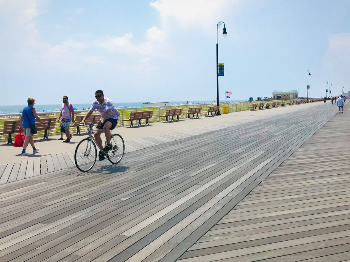 A biker riding a bicycle on the Long Beach boardwalk.