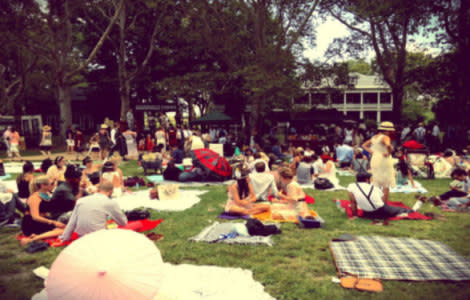 Revelers picnic on the lawn in front of historical brick building