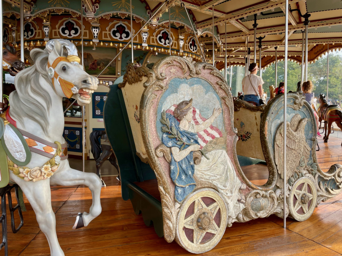 Standing figures on Jane's Carousel including a white horse and an Americana chariot