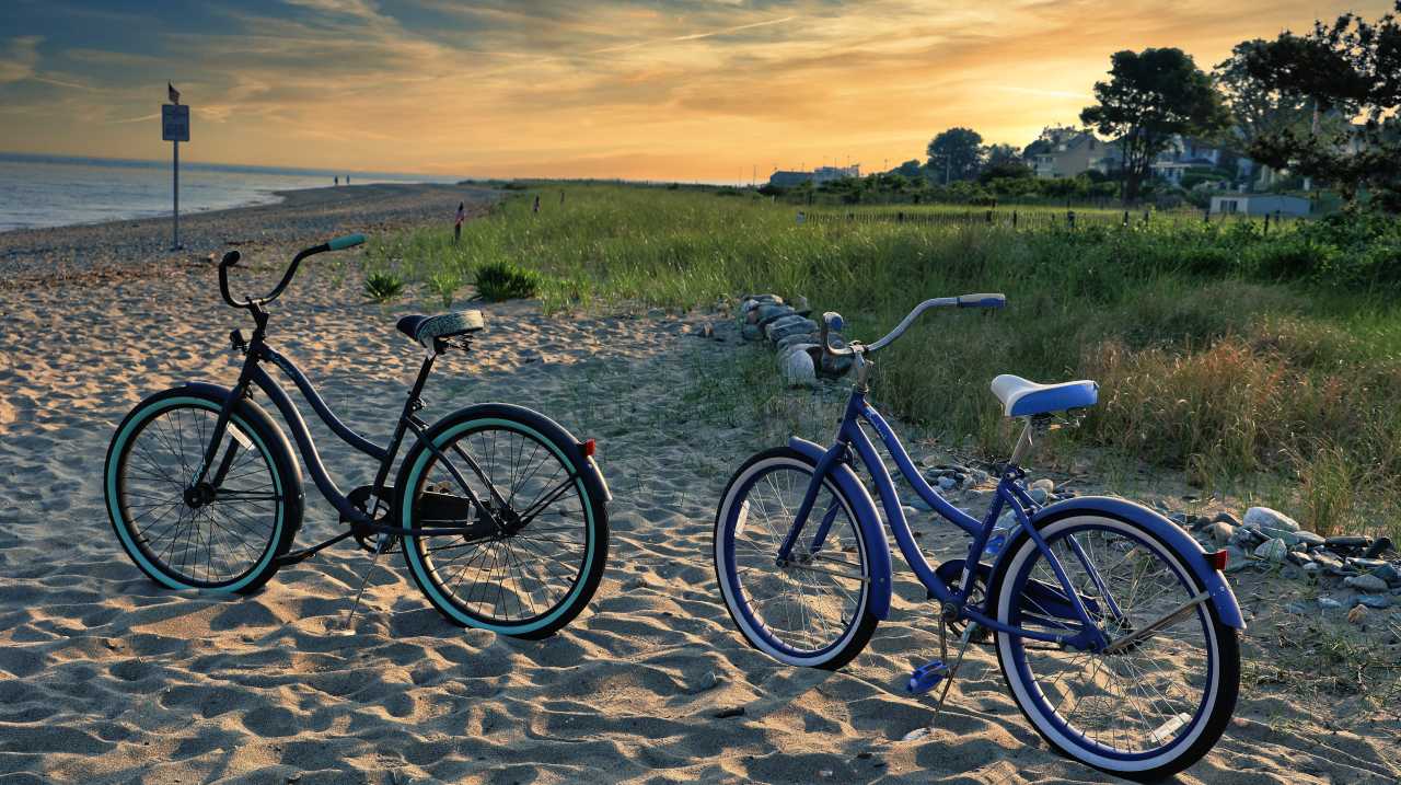 Two bicycles parked on a beach at sunset in Stratford, CT
