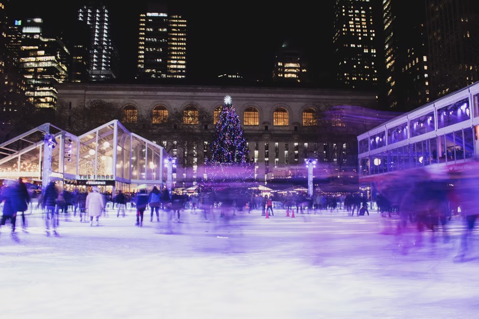 Night ice skaters on the rink at Bryant Park with the New York Public Library in the background