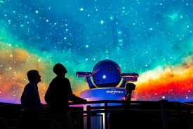 The silhouettes of two people looking up at the ceiling display at the Vanderbilt Space Observatory