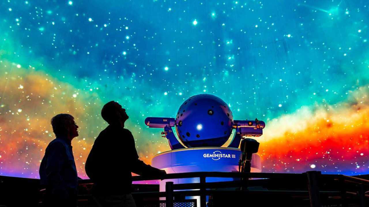 The silhouettes of two people looking up at the ceiling display at the Vanderbilt Space Observatory