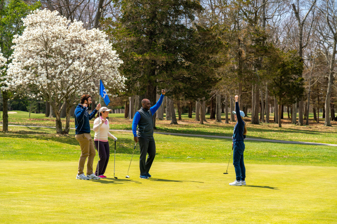 A foursome celebrating on the green at Sunken Meadow Golf Course