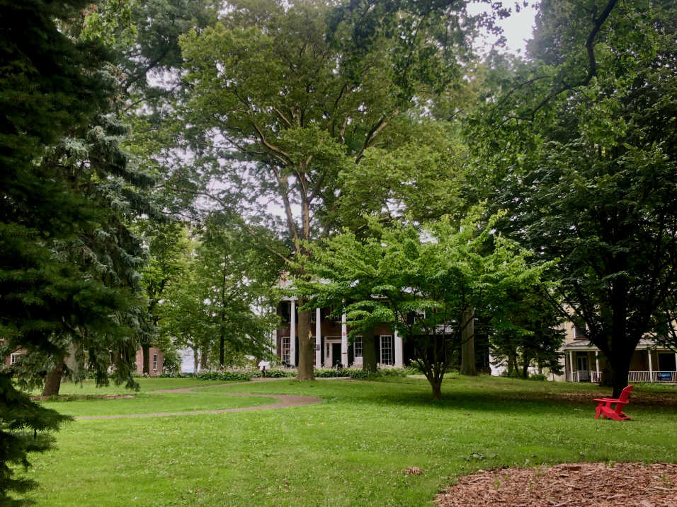 Historical brick buildings surrounded by trees with green lawn in foreground