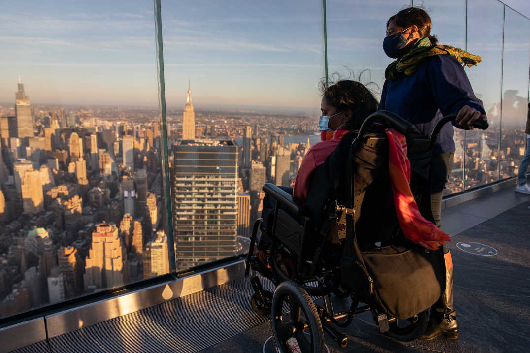 Two individuals, one standing and one in a wheelchair, looking out at the view from Edge in NYC