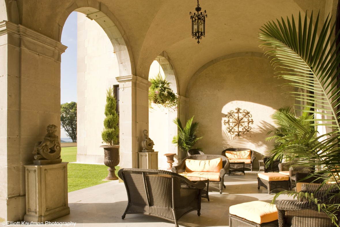 Sunlit nook of Oheka Castle decorated with comfortable wicker chairs and couches and palm trees