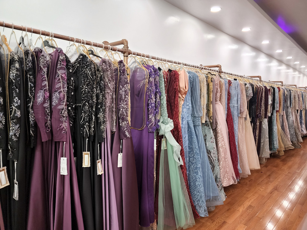 Row of colorful dresses hung on a long rack at Sarah Fashion