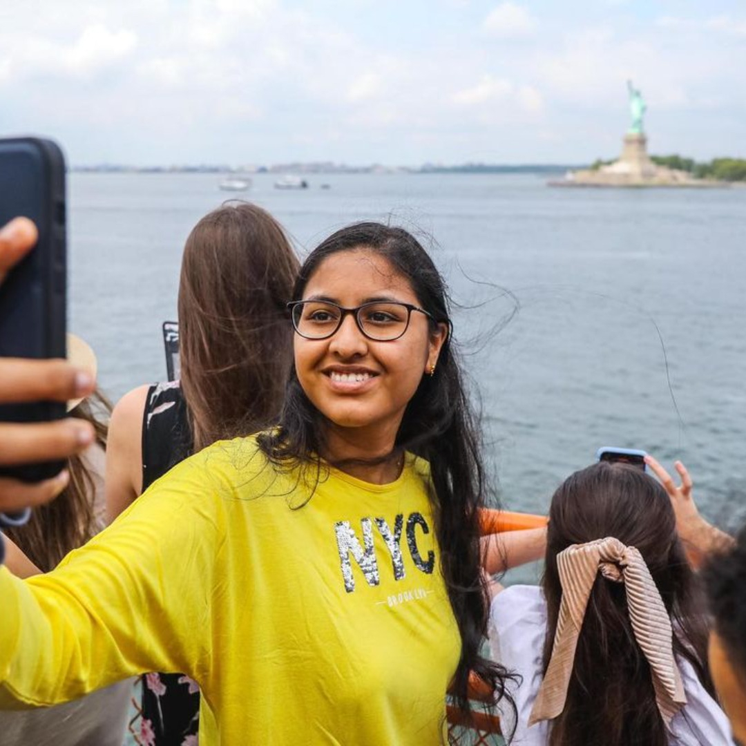 Woman takes seflie on the Staten Island Ferry with the Statue of Liberty in the background