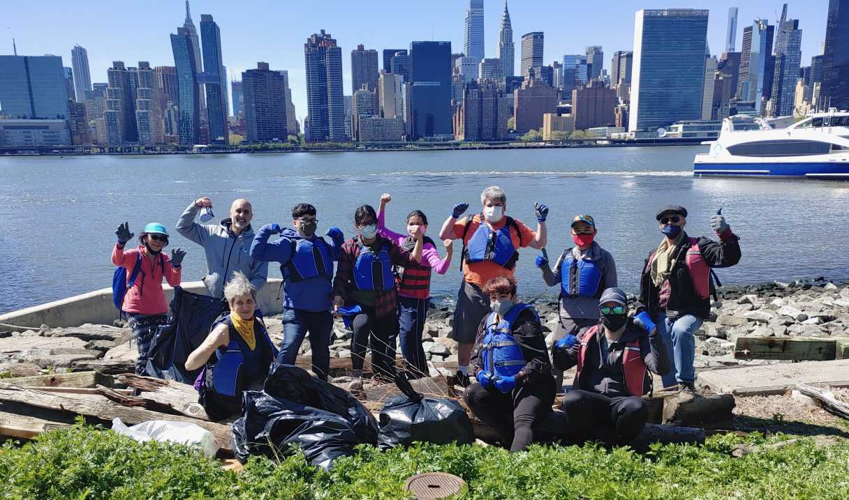 Riverkeeper cleanup crew posing in front of the East River in Long Island City with Manhattan midtown skyline in background