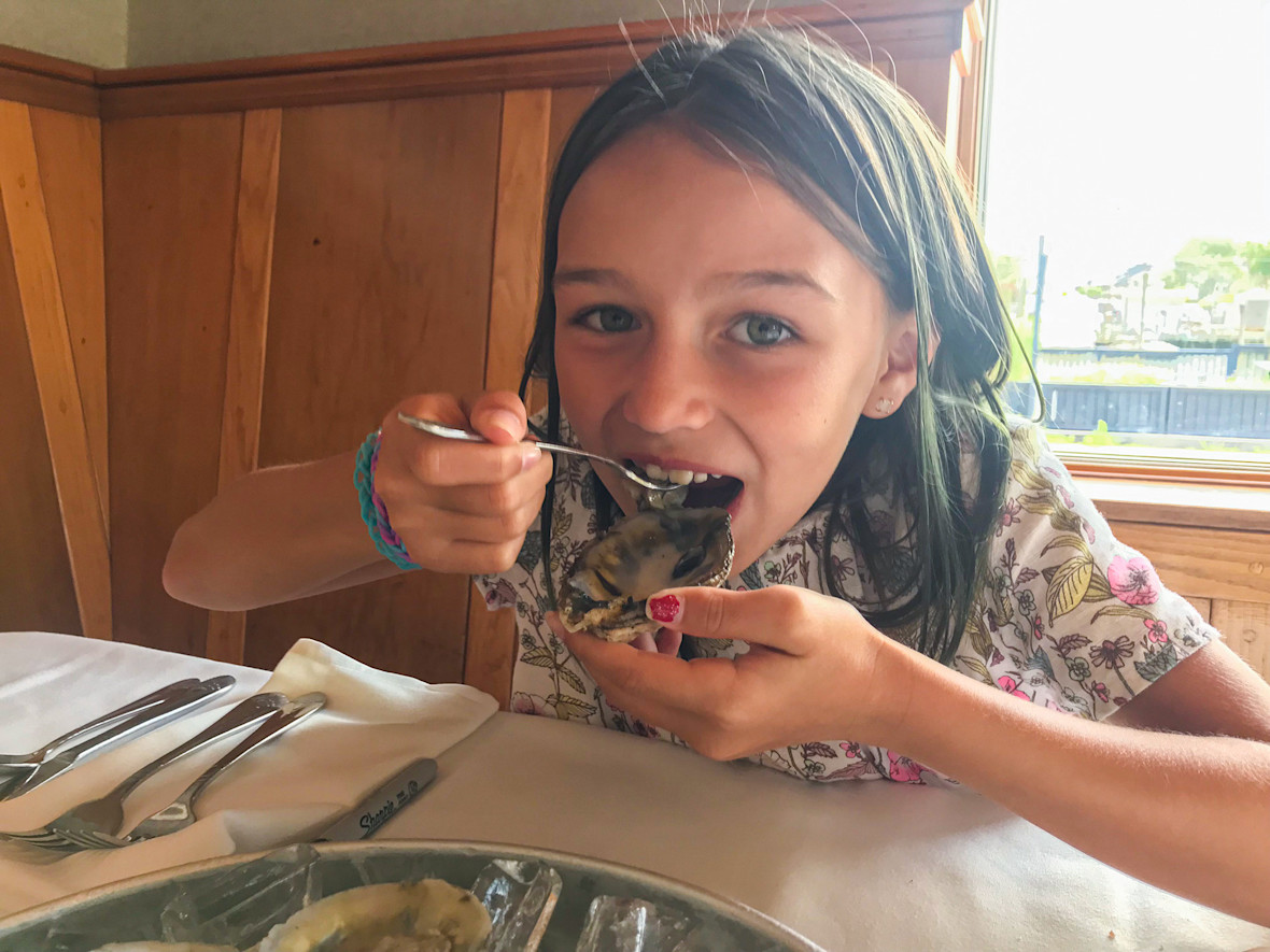 Young girl enjoys a raw oyster in Freeport.