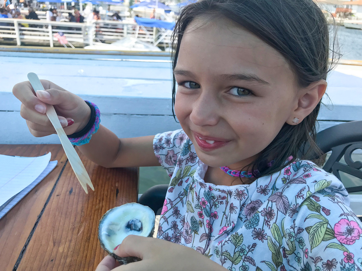 Young girl showing off finished raw oyster at Bracco's in Freeport