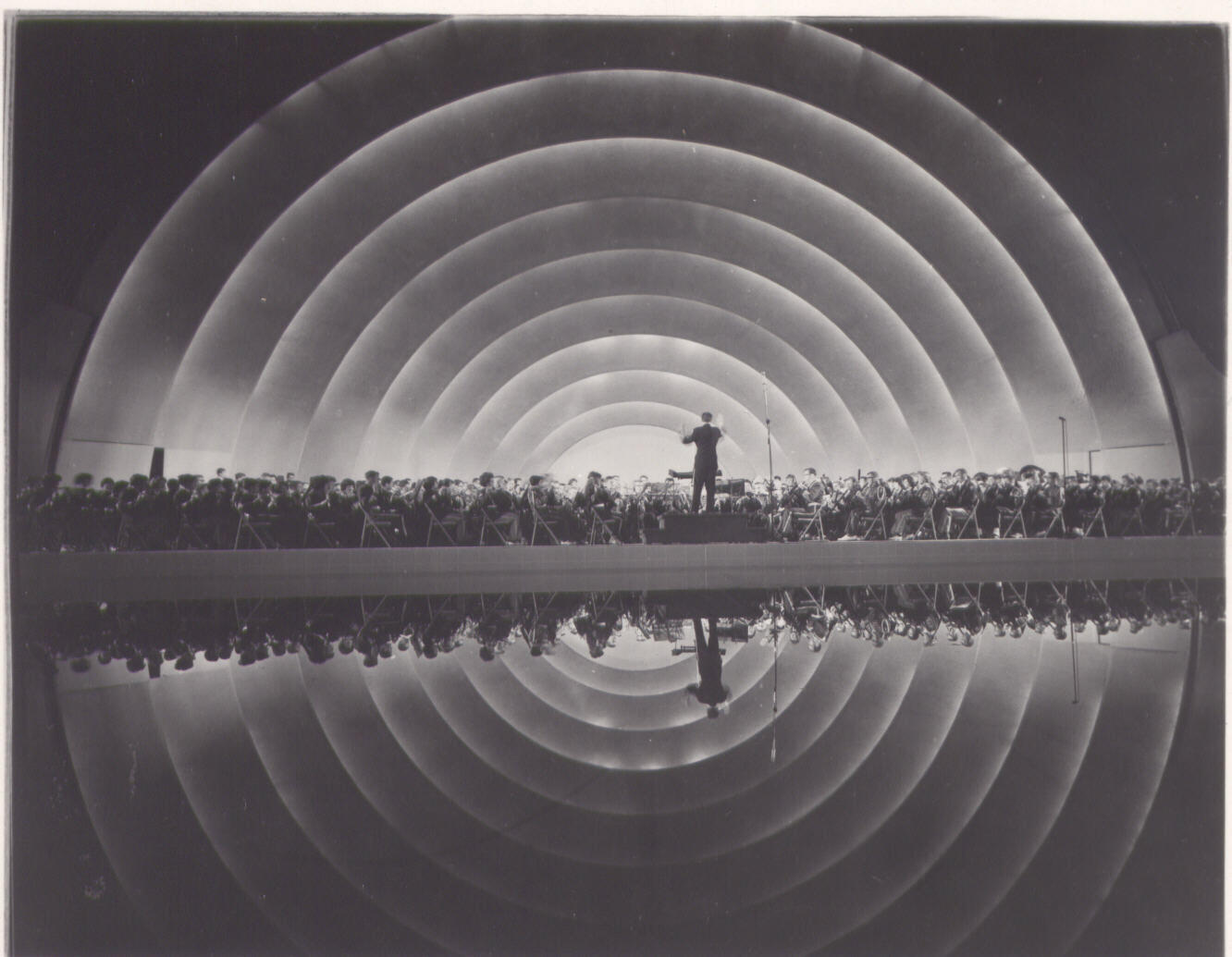 Leonard Bernstein conducts the New York Philharmonic at the Hollywood Bowl, surrounded by the Bowl shell and reflection pool, circa 1963.