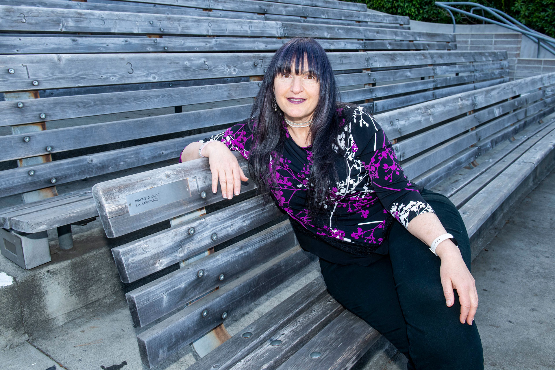 Seat-naming donor Dianne Waldman posing with her named bench seat. Her plaque reads: "Dianne "Dijou's" L.A. Happy Place."