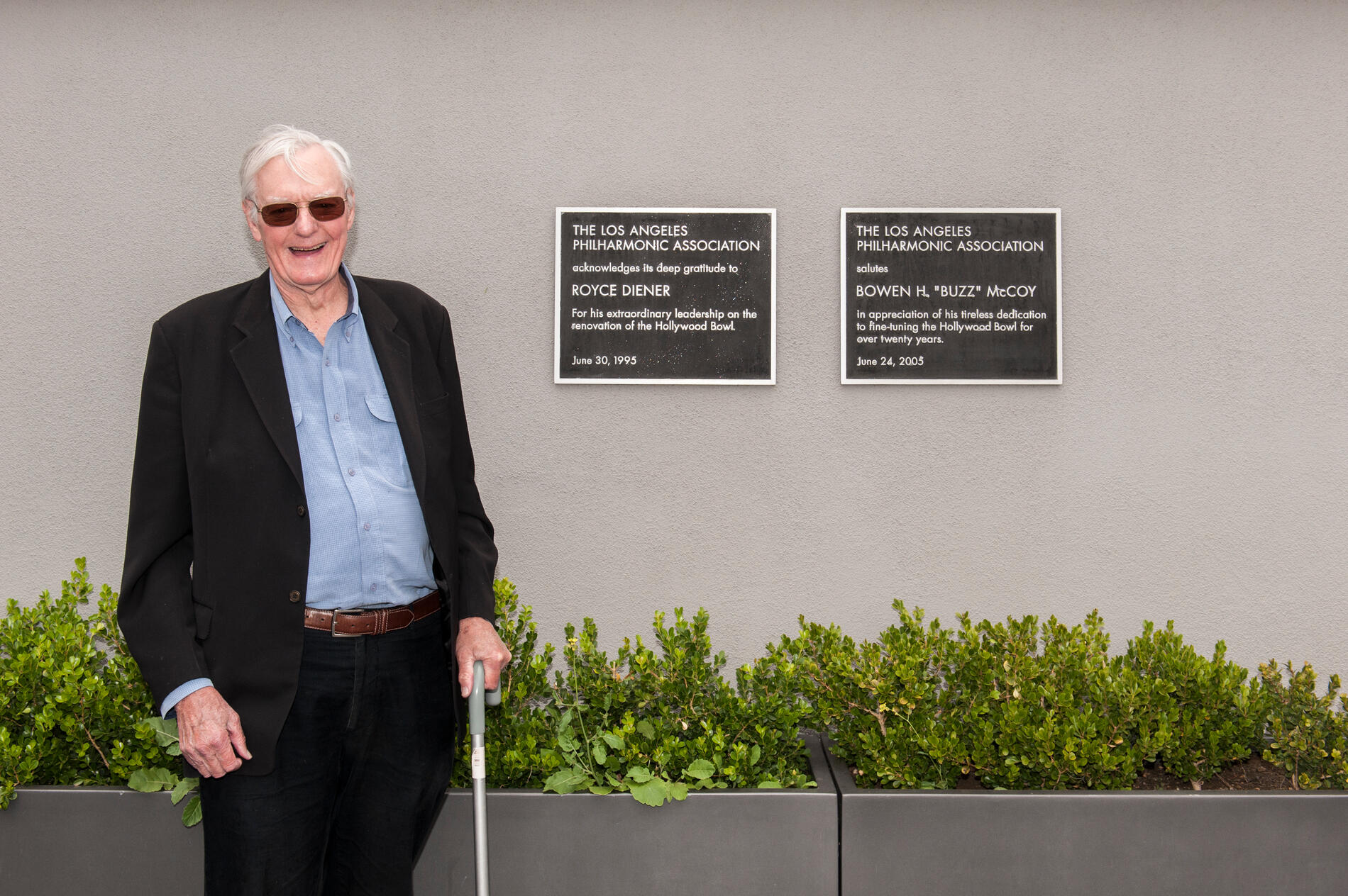 Buzz McCoy in front of plaques honoring his and Royce Diener’s leadership at the Bowl