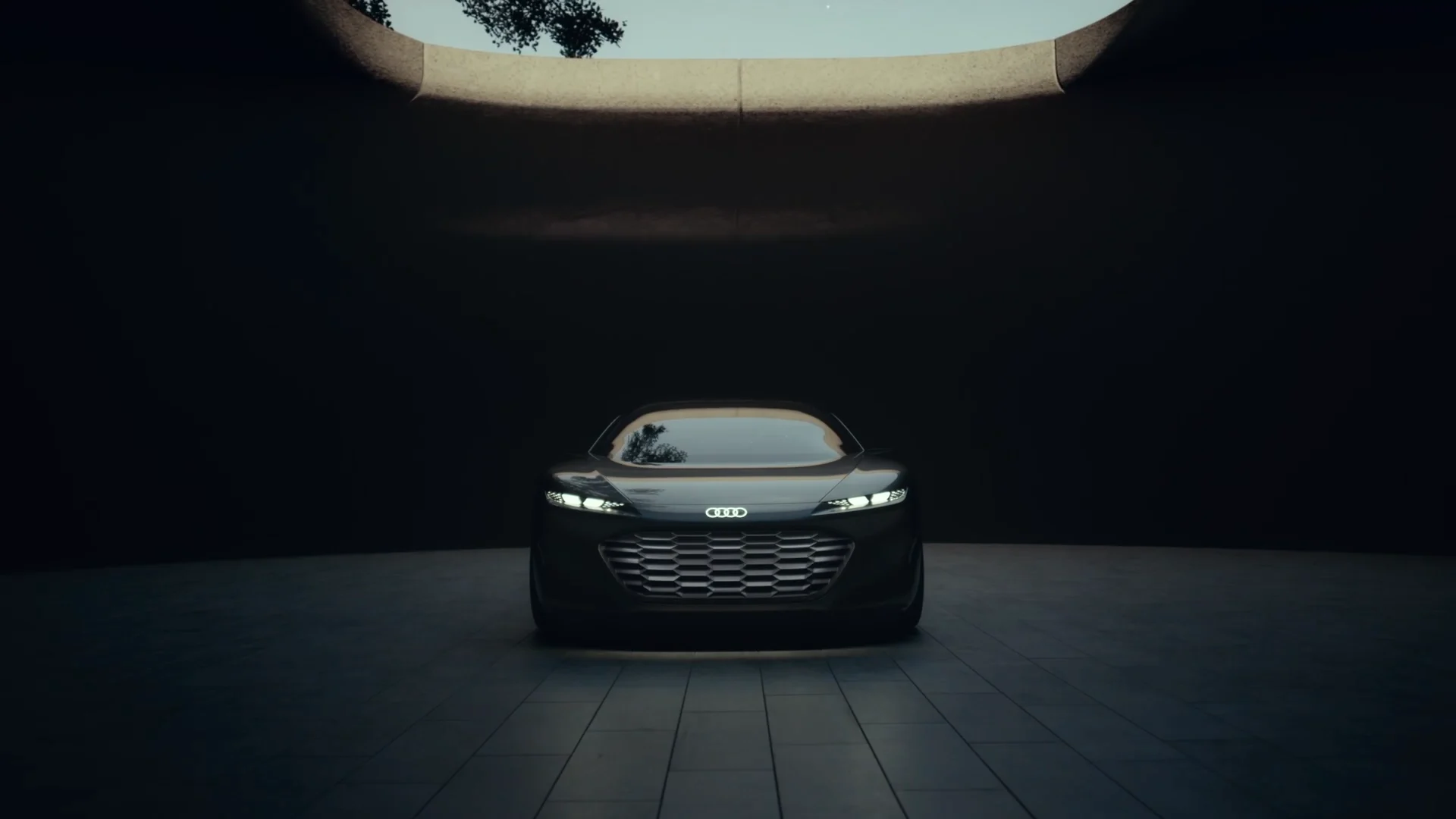 a black audi concept car in a concrete textured room with an open roof. The sky and a tree are visible through the roof