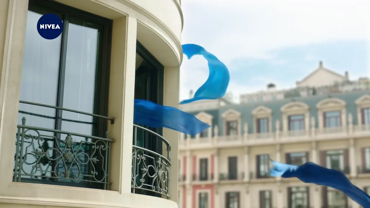 several blue silk scarfs flying into the open window of a old building