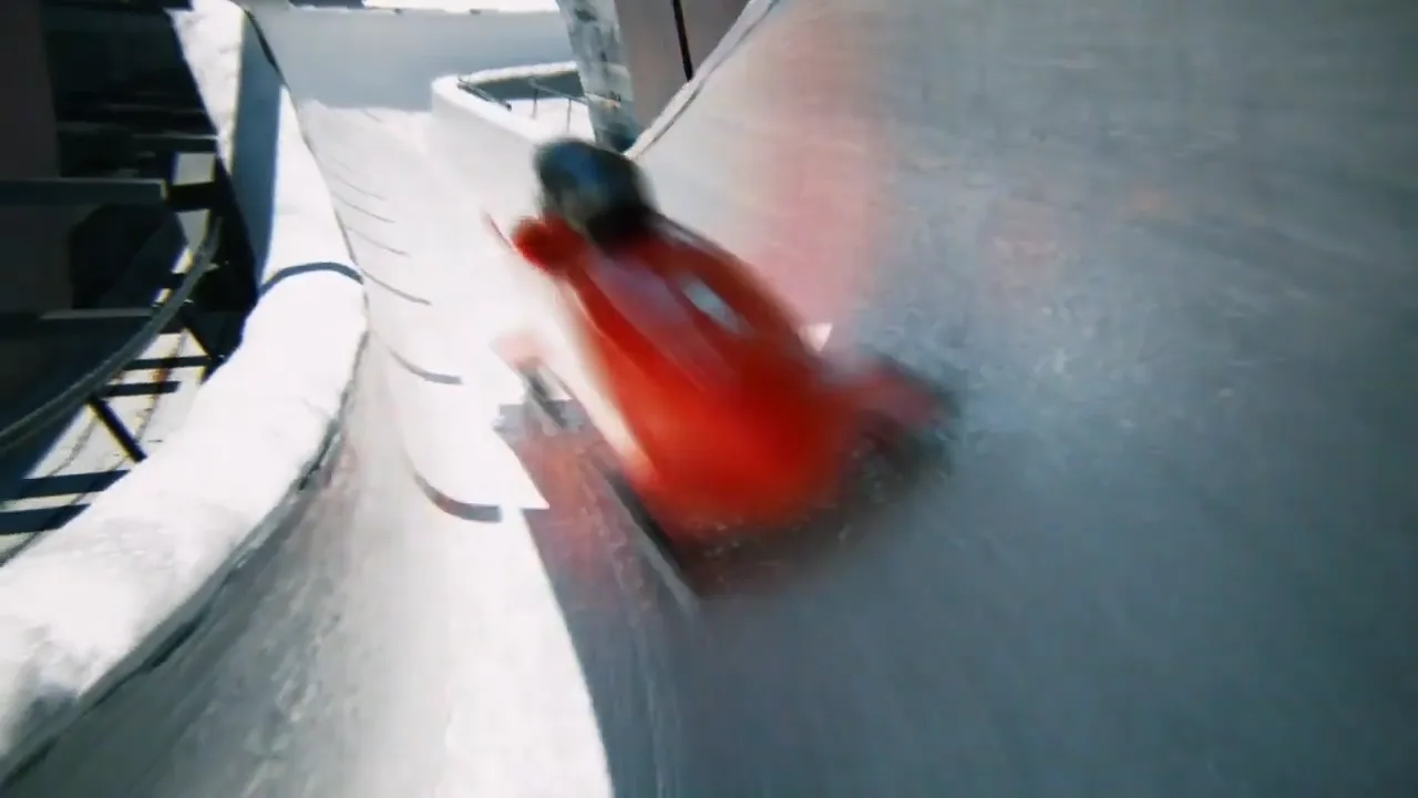 a red bobsleigh with two drivers in it speeding down a bobrun