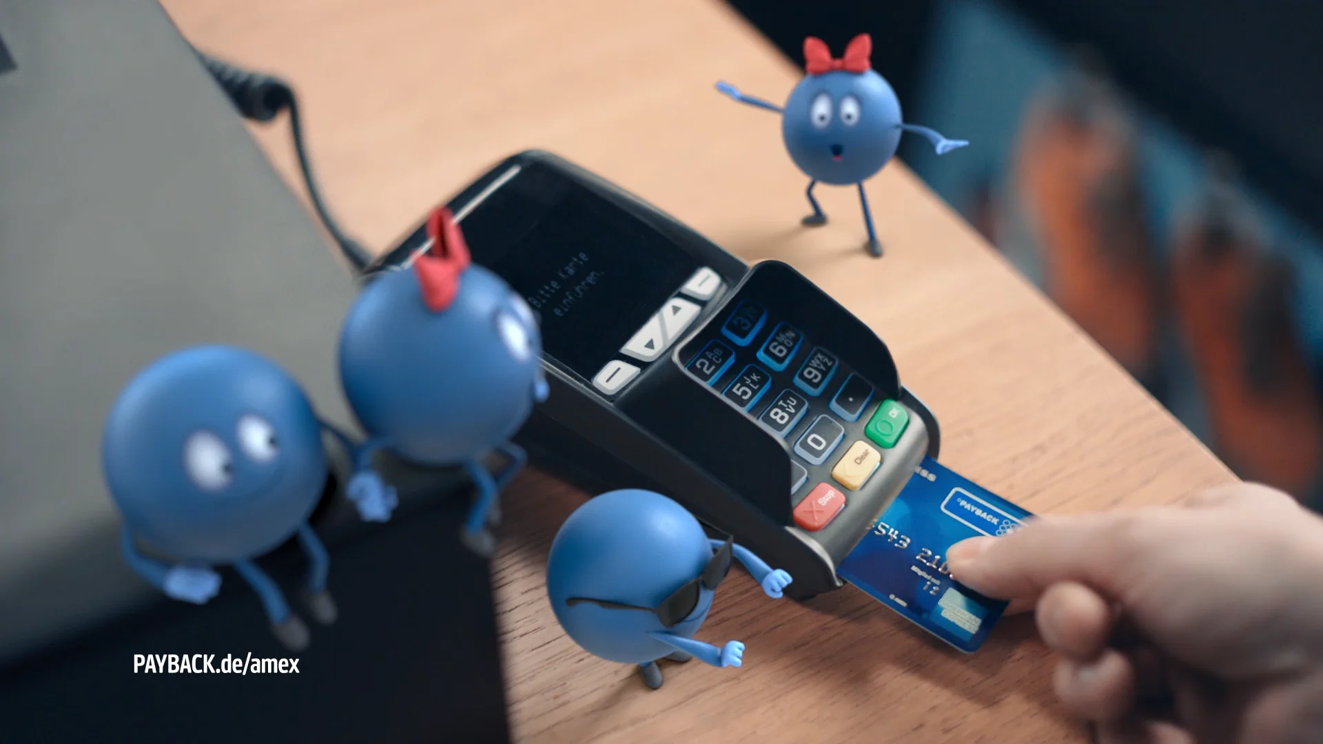 four blue 3d characters with different accessoires smiling and performing on a till tape next to a card reader with a payback card in it