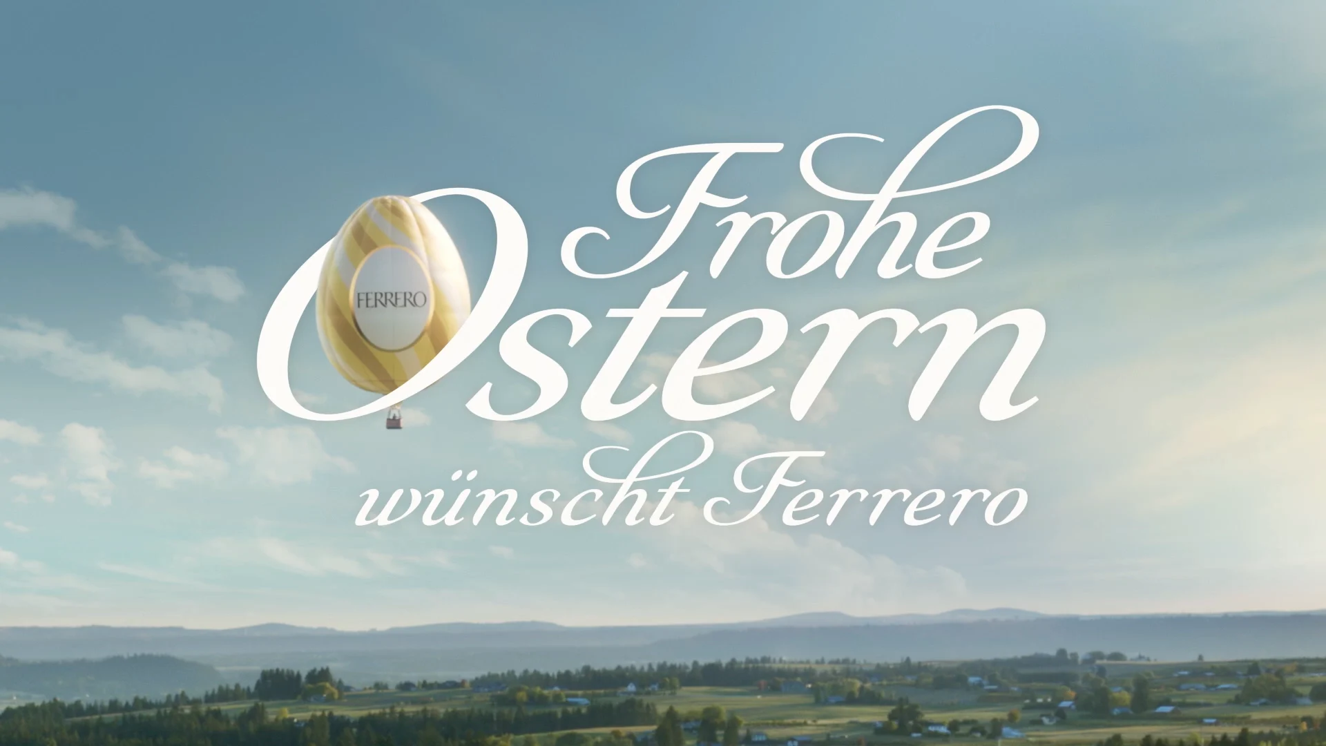 The Claim FROHE OSTERN WÜNSCHT IHNEN FERRERO is written into the sky above a green landscape. A hot air ballon shaped like an Easter egg is flying in the letter O