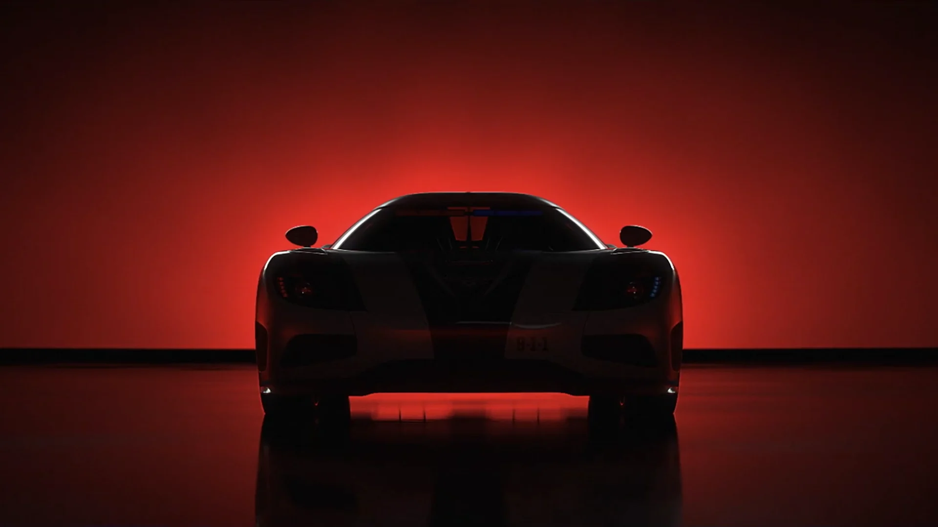 an undefined racing car in the shadow in front of a red glowing backlight