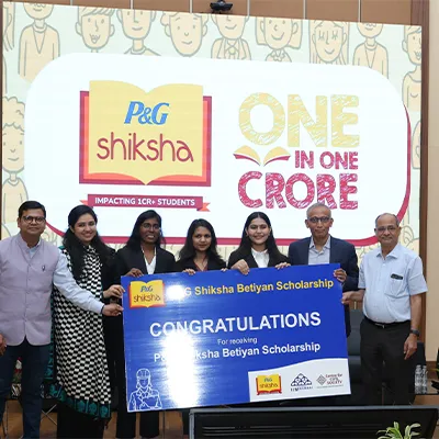 Group of scholarship recipients and presenters holding a P&G Shiksha Betiyan Scholarship congratulatory sign at an award ceremony in India.
