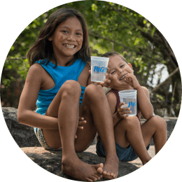 Children smiling and holding a glass of purified water