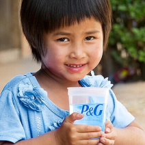 A child smiling and holding a glass of purified water