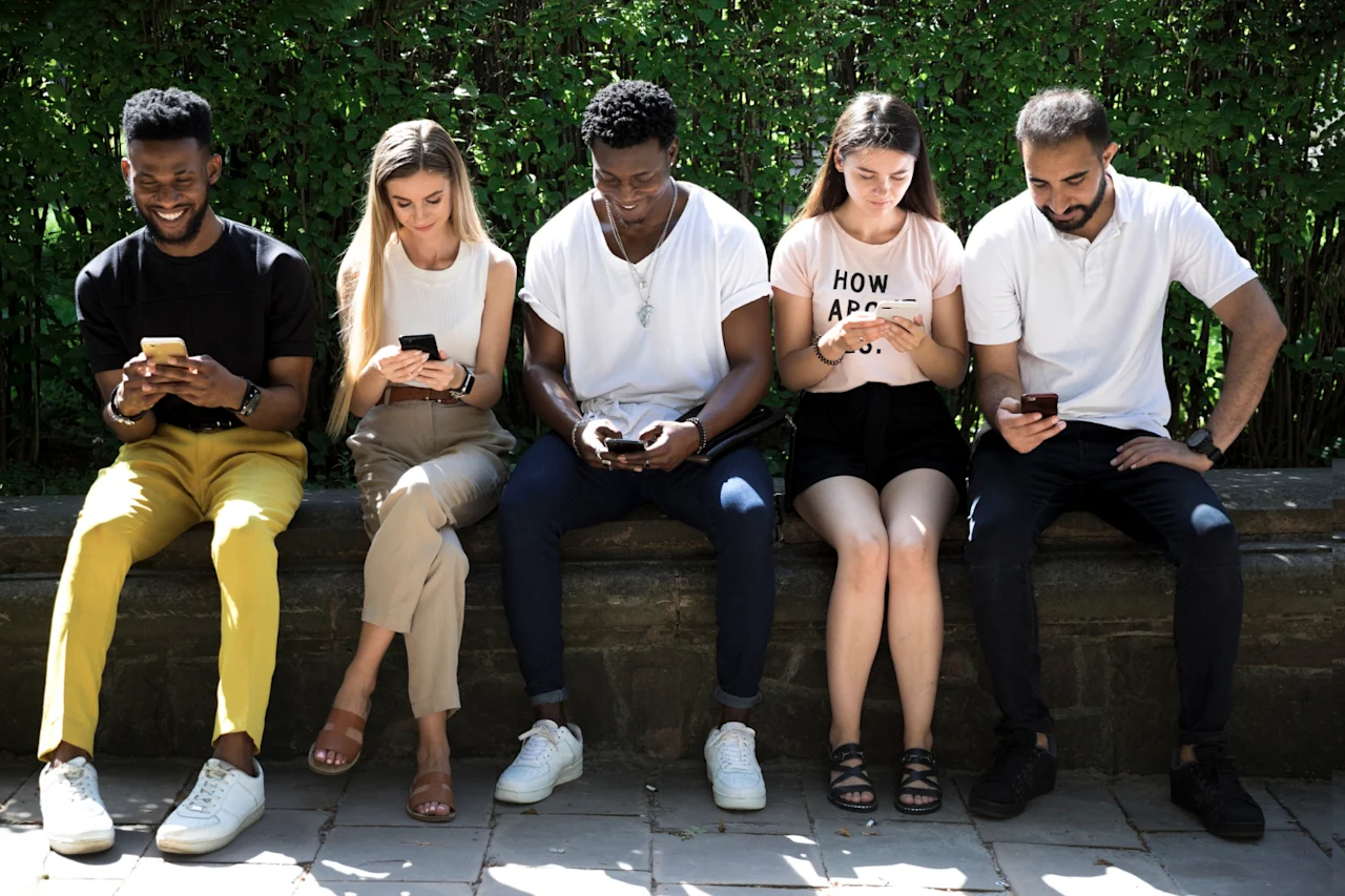 Five people that are all focused on their cell phones