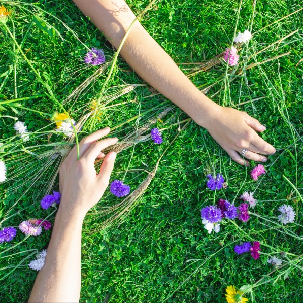 Hands on grass with flowers strewn about