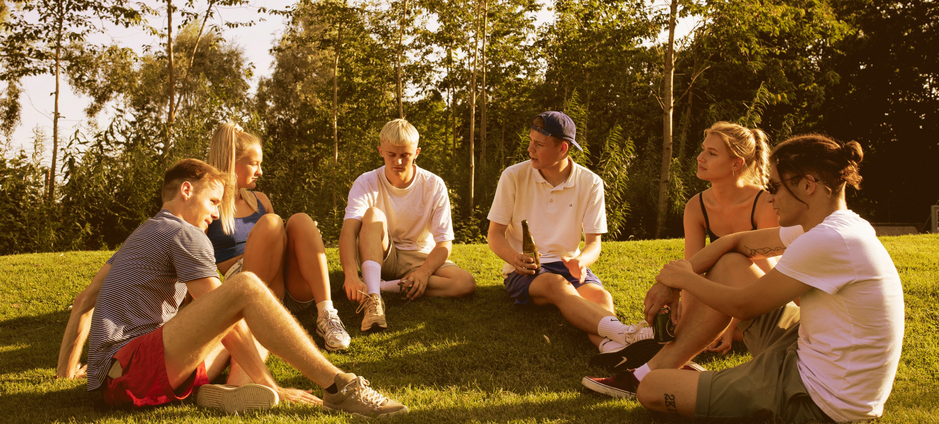 Six young people relax and drink beer in the sun