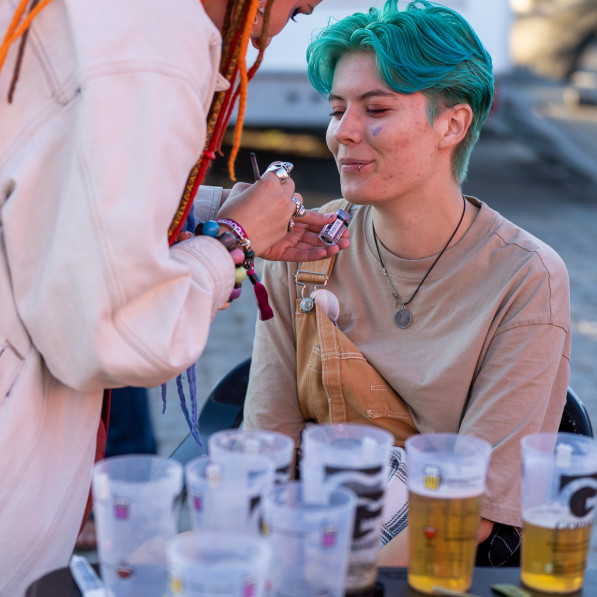 Kvinde med dreadlocks lægger glittermakeup på kvinde med blåt hår på Kontur 22