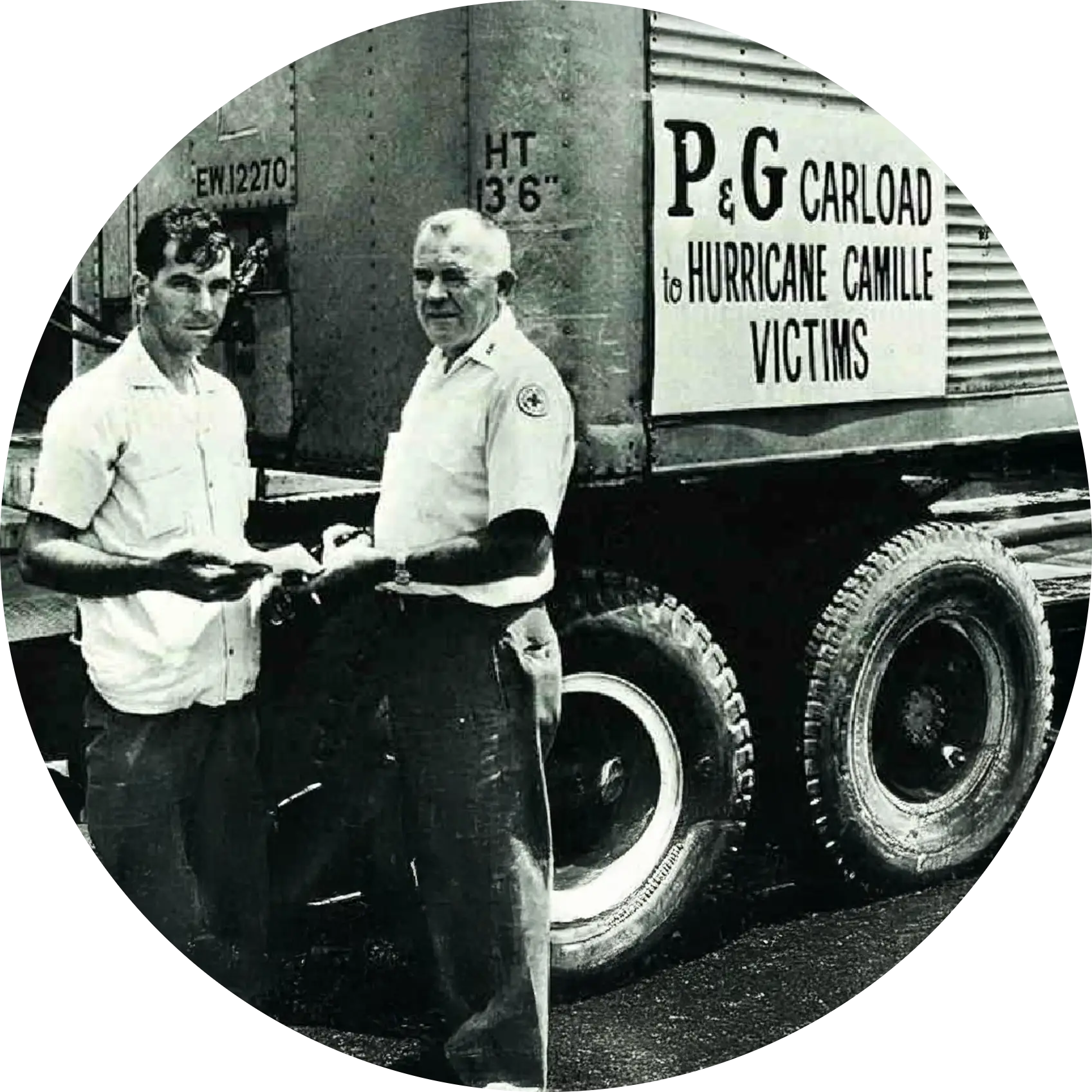 Historic photograph of two people standing beside a truck labeled 'P&G carload to Hurricane Camille victims'