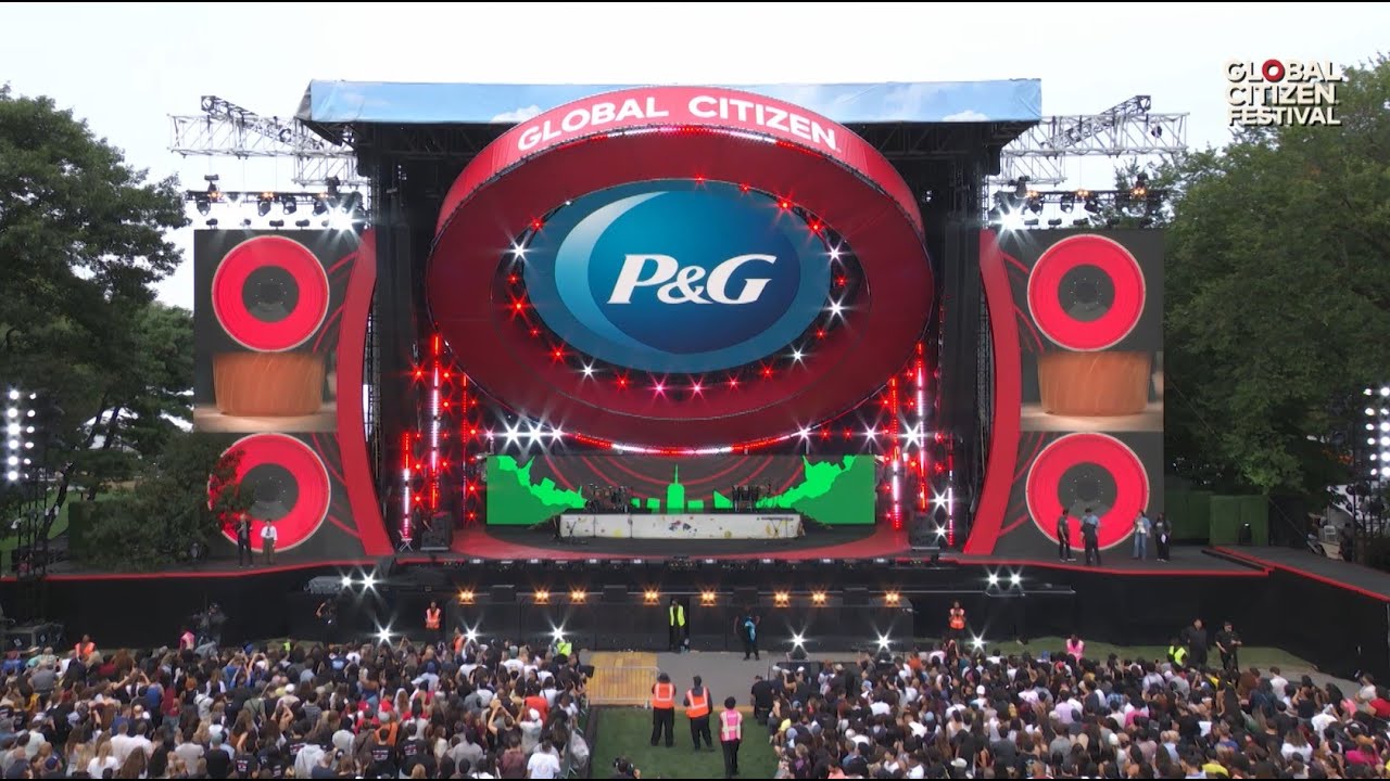 An outdoor stage. A large round fixture hangs above the stage with the words “Global Citizen.” A round blue logos says “P&G.”